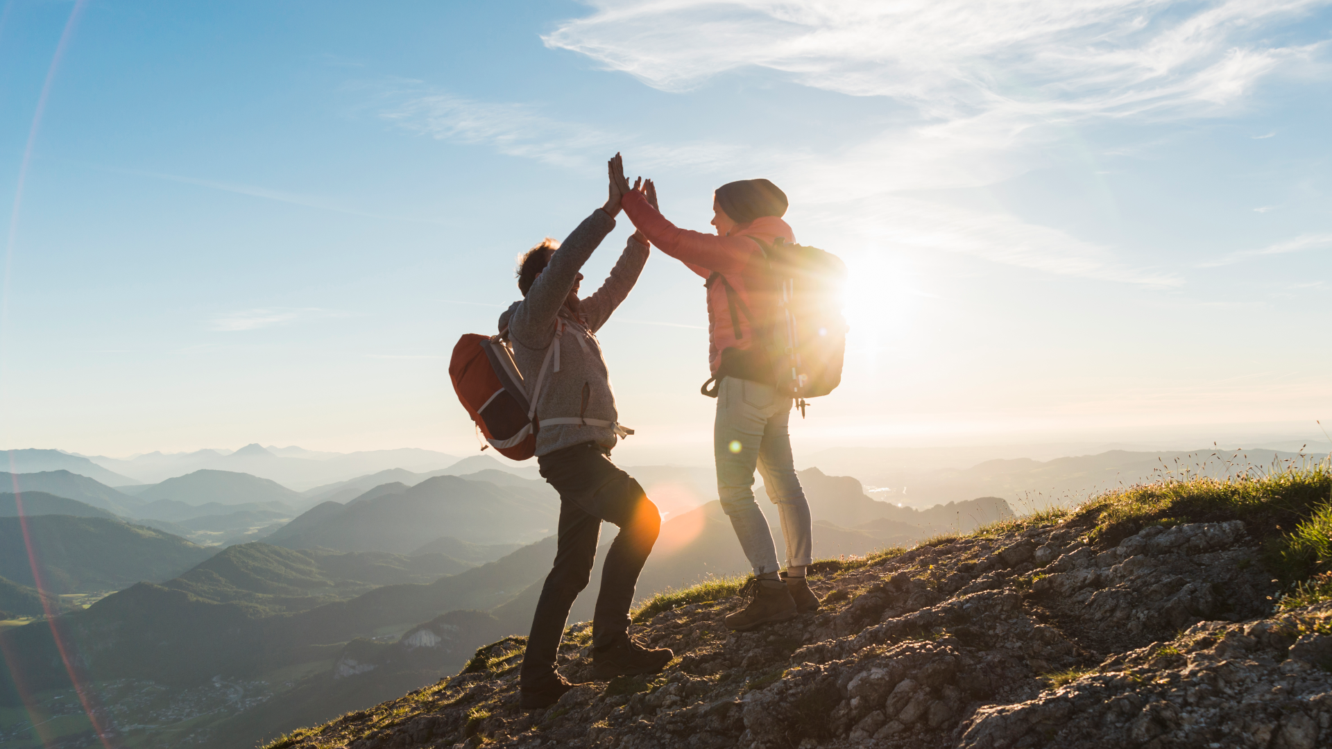 Two people high fiving at the top of a hill on a hike