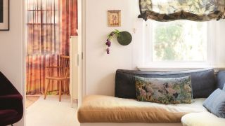 living room with sheer floral roman blinds, a banquette seat with patterned rug, stone coffee table and white floors and walls