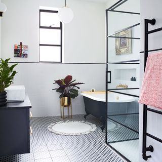 monochrome bathroom with black roll top bath, crittalstryle shower enclosure and patterned tiled flooring