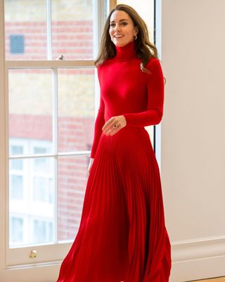 Kate Middleton wearing a red turtleneck jumper and red pleated skirt