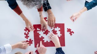 People solving a puzzle from above