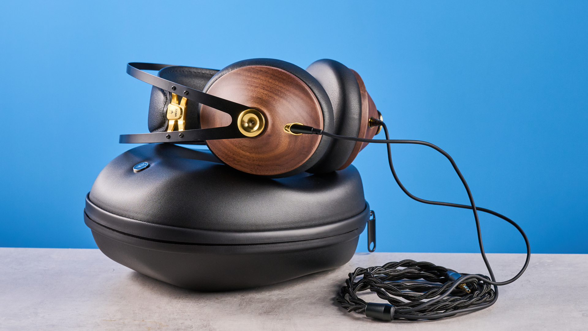 the meze 99 classics 2nd gen headphones with walnut finishes and gold touches against the blue tom&#039;s guide background