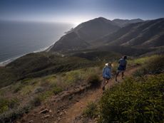 Hikers look down at the Pacific Ocean