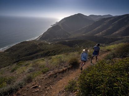 Hikers look down at the Pacific Ocean