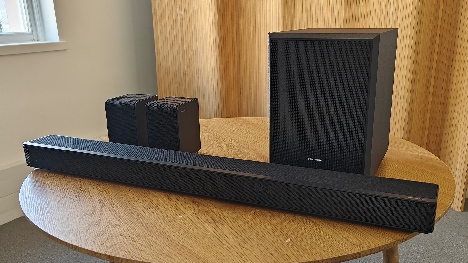 The Hisense AX5125H Dolby Atmos soundbar system, pictured on a round, wooden table