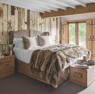 Wood clad bedroom with distressed walls, woven bed and faux fur throw
