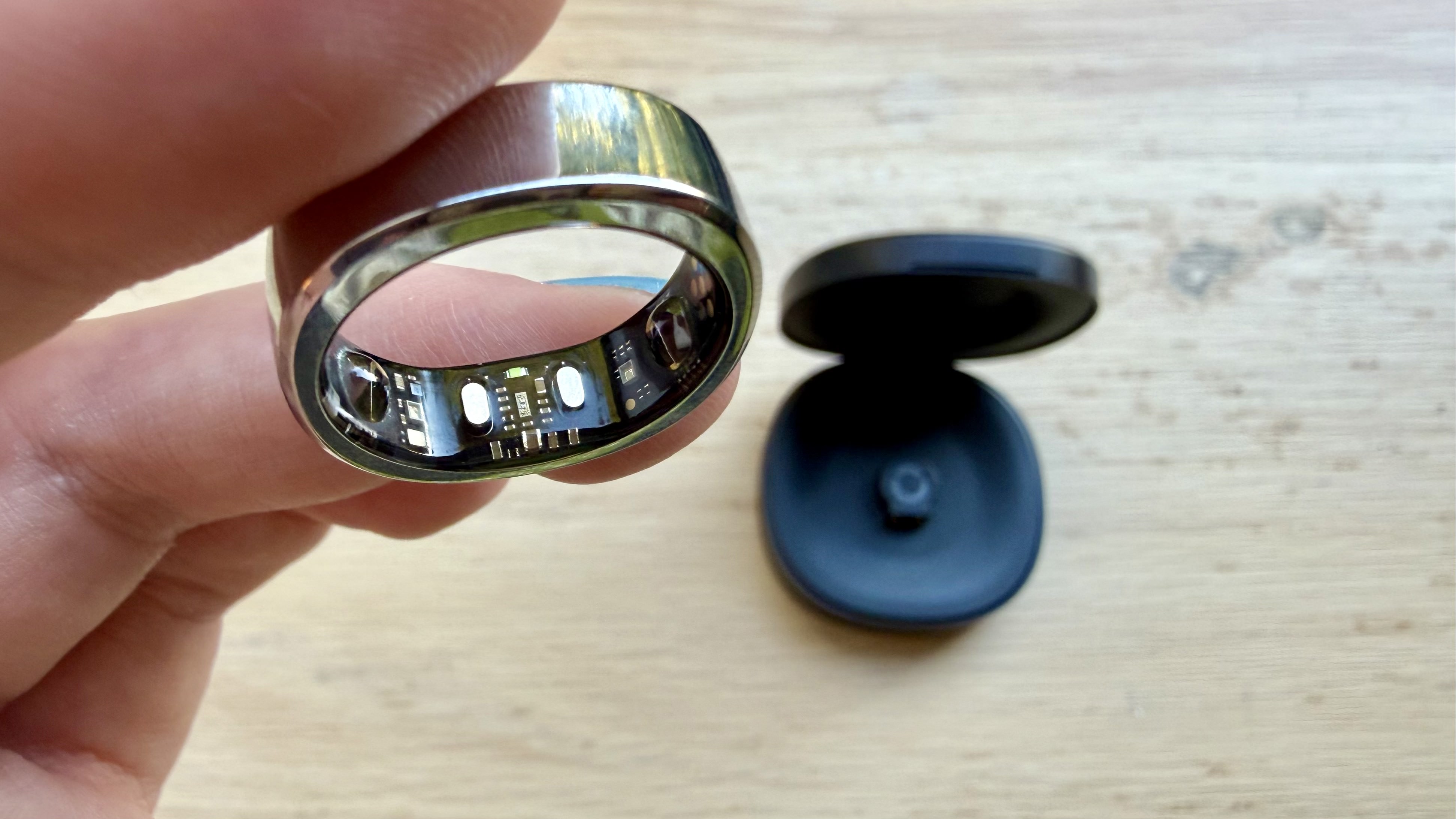 Becca holding the RingConn Gen 3 in silver above a wooden surface