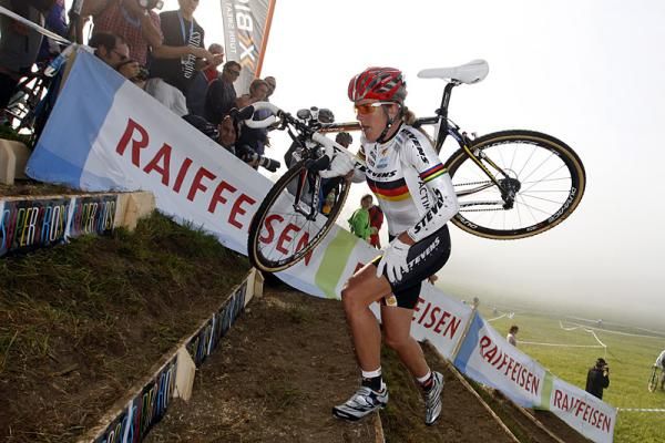 Hanka Kupfernagel shoulders her bike on the stairs.