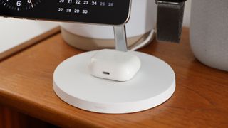 Close up of AirPods on a Belkin BoostCharge Pro 3-in-1 Wireless Charger with MagSafe 15W on a wooden desk