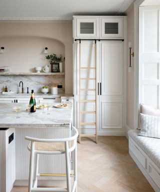 white kitchen with white island, marble worktops and window seat