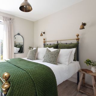 white bedroom with bed with green throw and cushions