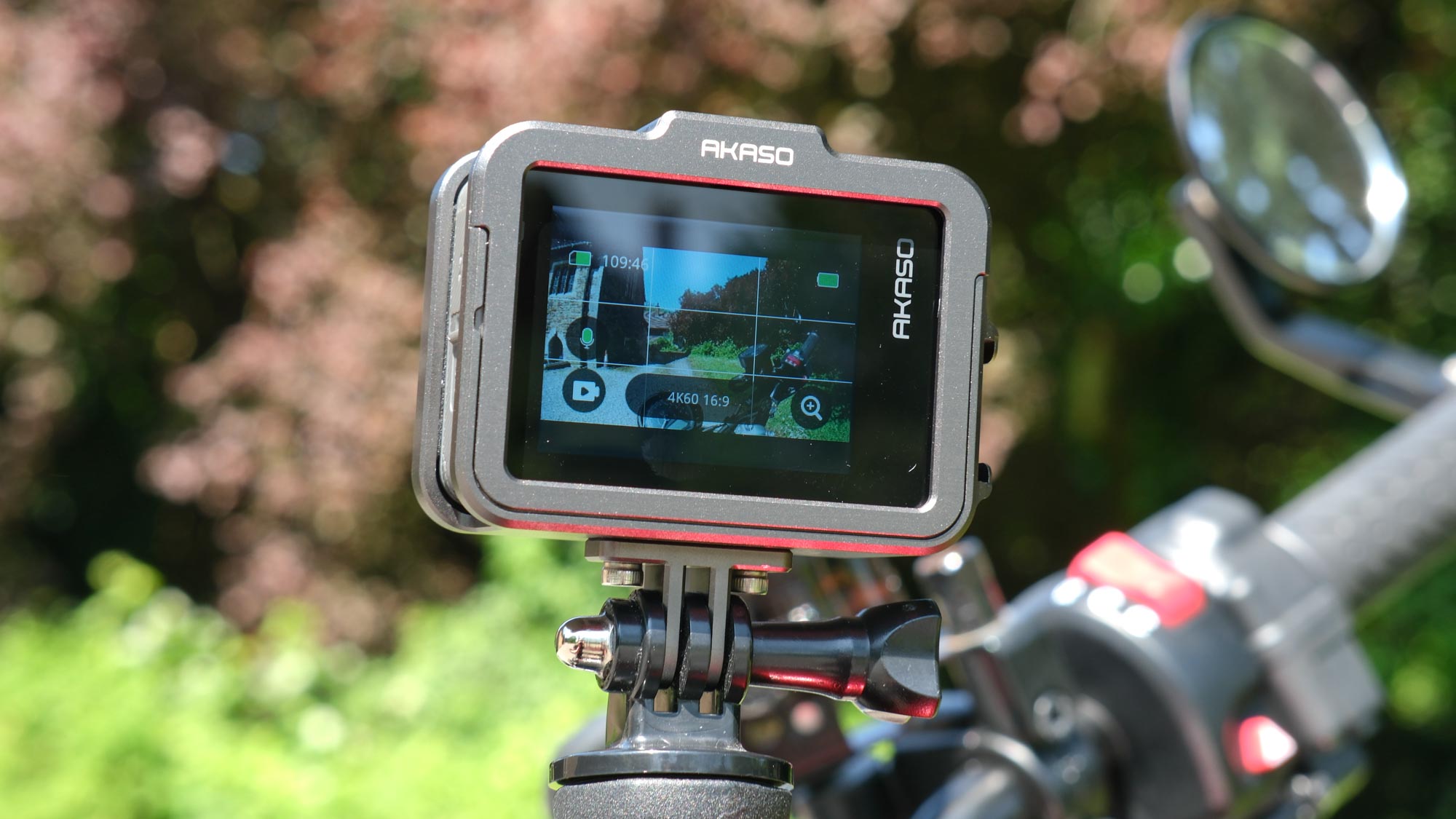 A photo of the rear screen of the Akaso Brave 8 Lite against a green, out of focus background.