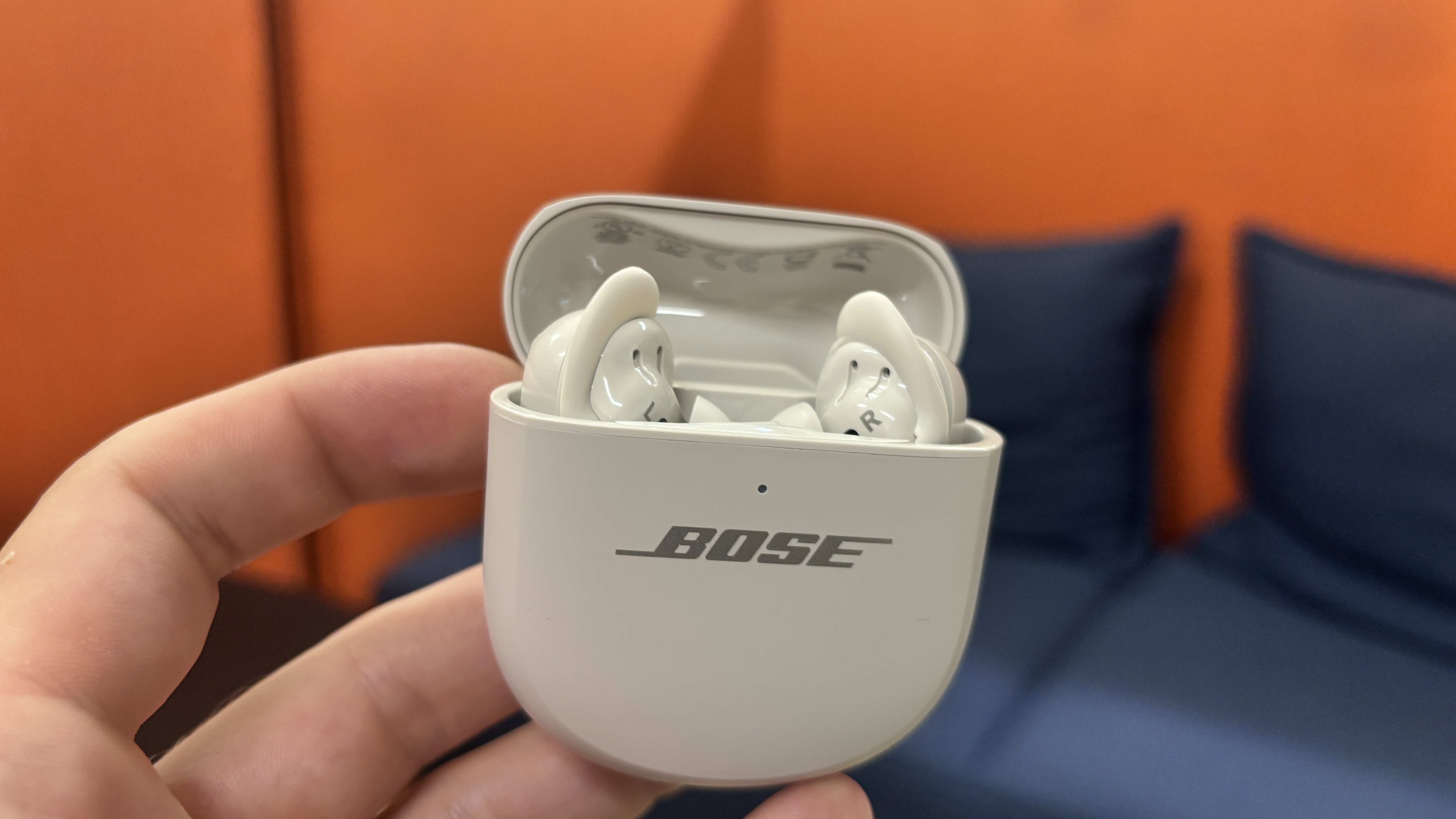 Bose QC Ultra Earbuds (2nd Gen) earbuds and case in white finish held in hand