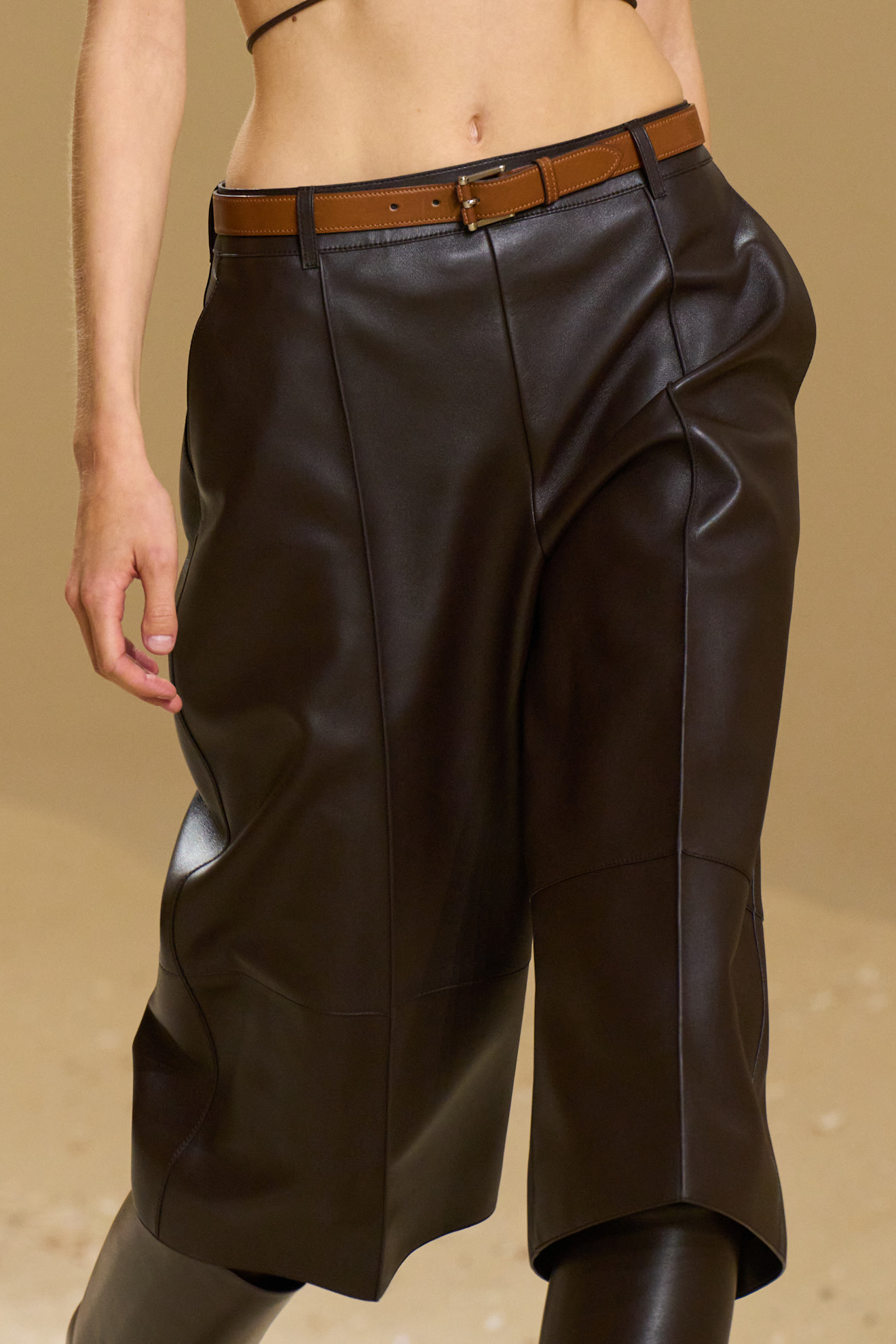 Image of the Hermes Spring/summer 2026 runway. The model wears brown leather long Bermuda shorts.
