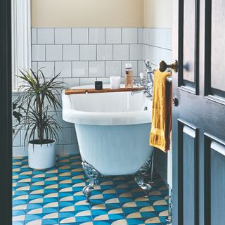 A bathroom with a tub and a brightly patterned tiled floor