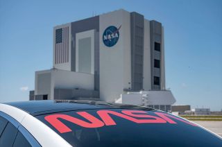 SpaceX's Tesla Model X astronaut transfer vehicle features NASA's resurrected, retro logotype, the red "worm," across its rear window.