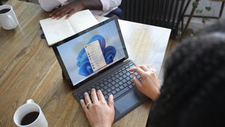 person typing on Windows 11 laptop in meeting