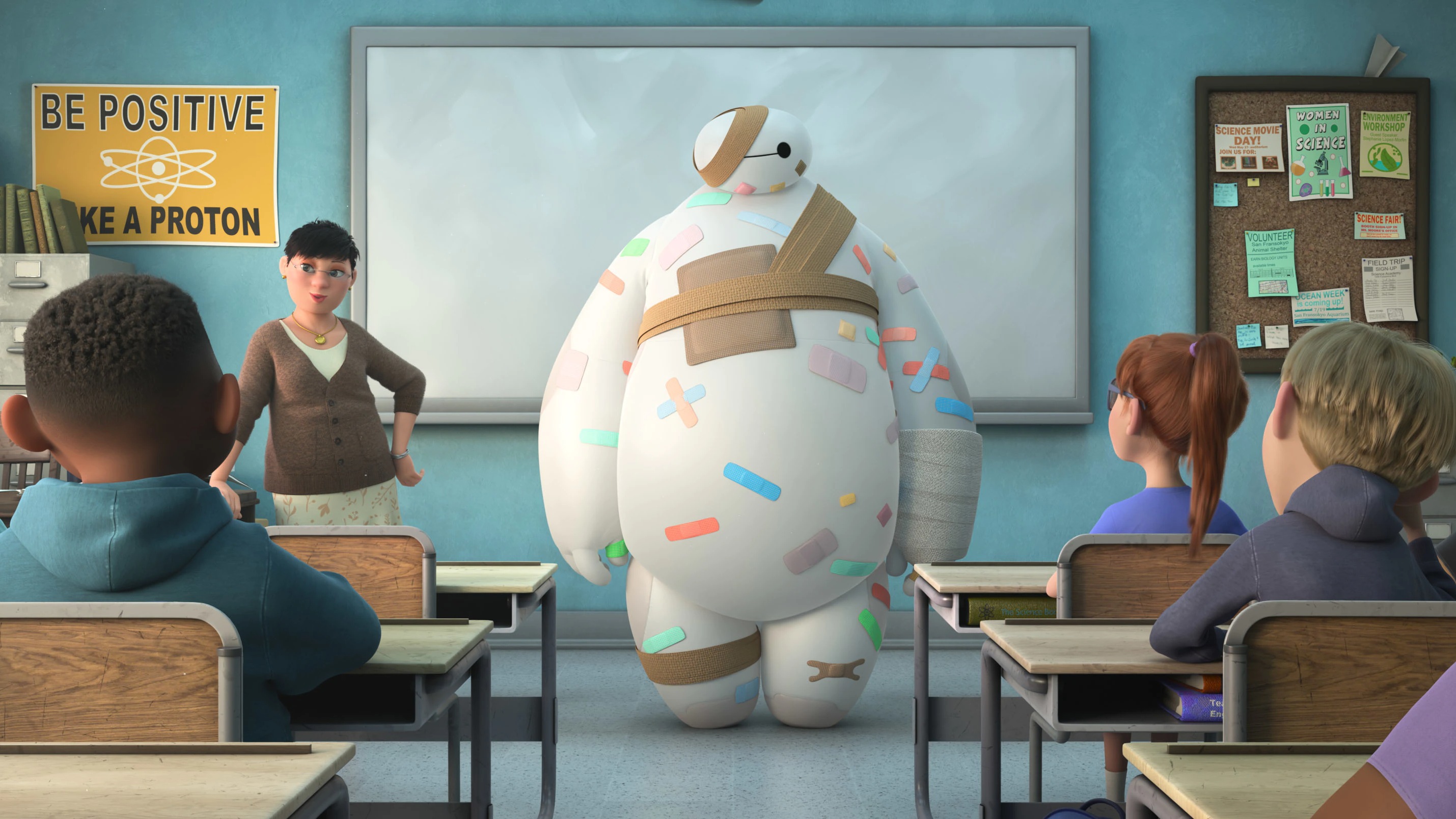 Baymax! står foran en klasse i et klasseværelse. Han er dækket af plastre og forbindinger