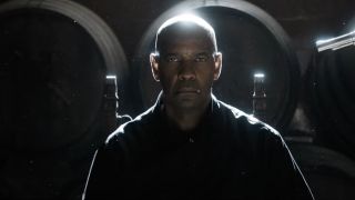 Denzel Washington held at gunpoint sitting in front of barrels in The Equalizer 3.