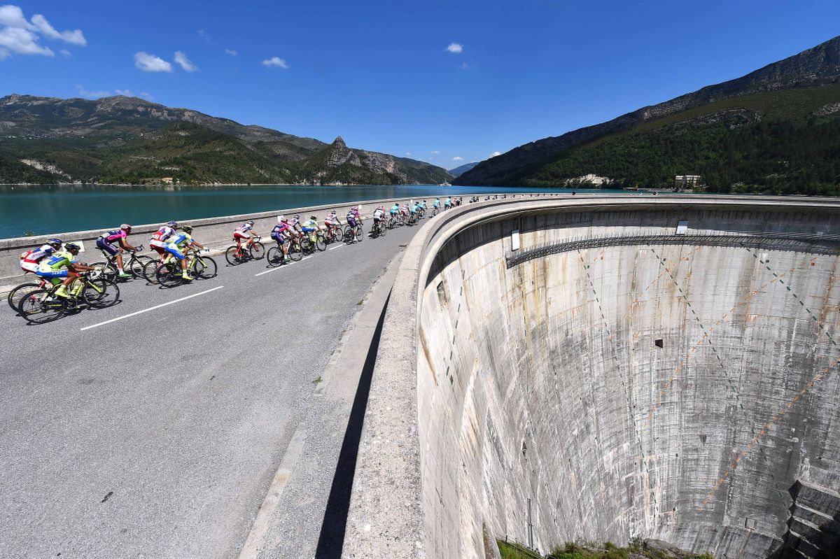 The peloton rides over a dam