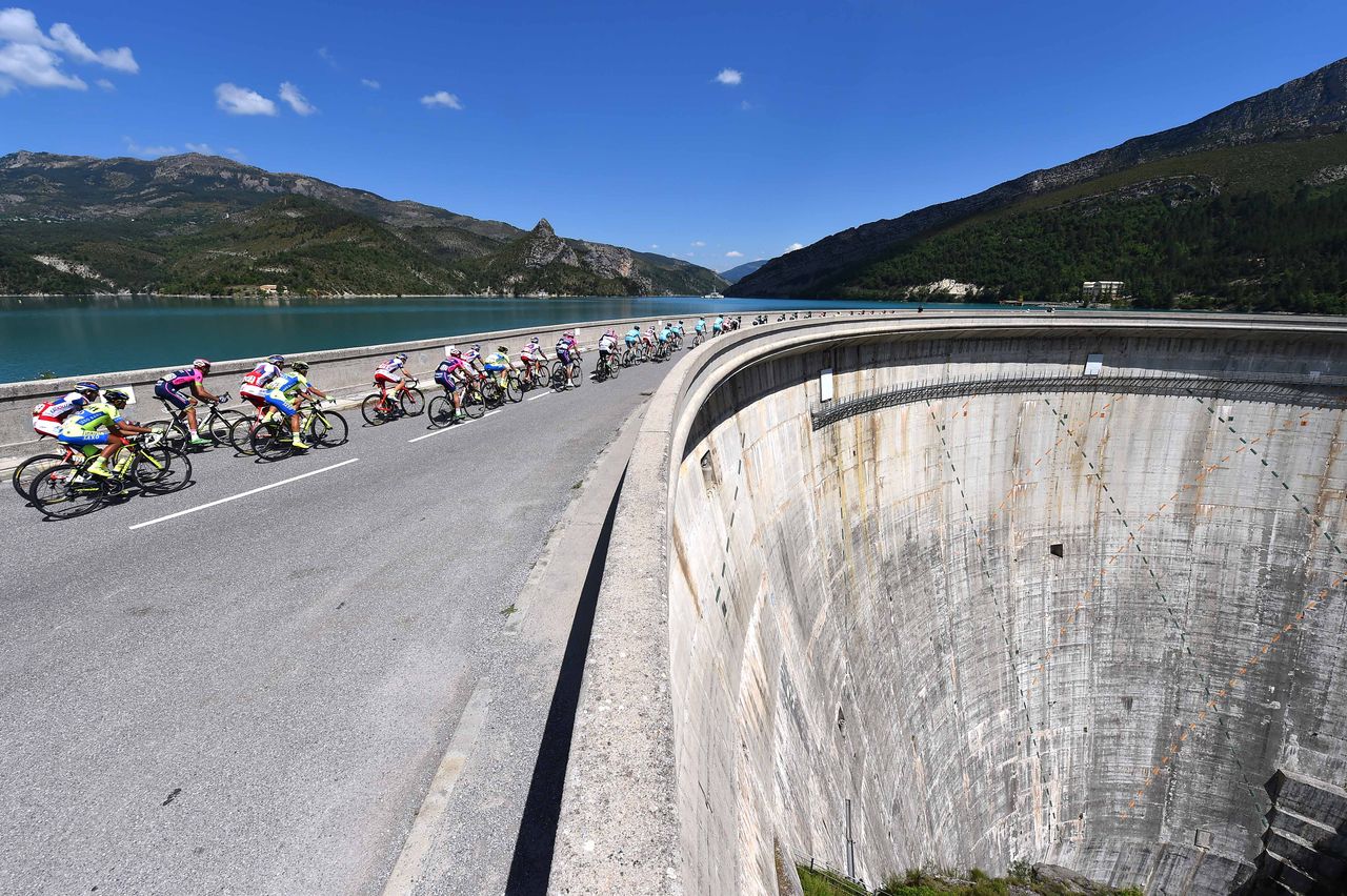 The peloton rides over a dam