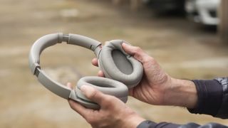 A person holding the sony wh-1000xm4 headphones up so you can see inside the cups