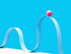 a digital image of a little red ball on the crest of a wave formed from blue paper and a blue background