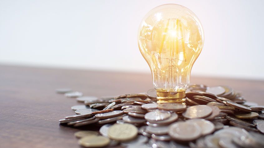 Light bulb and pile of coins