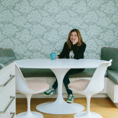 Image of a woman dressed in black witting in a seafoam green room.