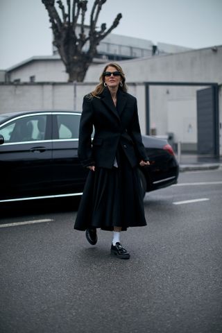 woman wearing black coat, loafers, and socks