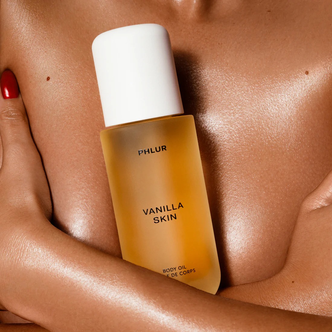 woman with glowing skin holding phlur vanilla skin body oil against chest