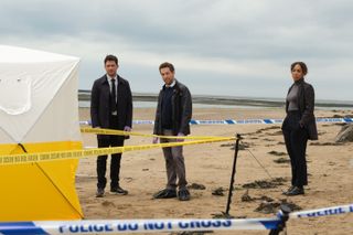 Matthew Venn (Ben Aldridge), Ross Pritchard (Dylan Edwards) and Jen Rafferty (Pearl Mackie) stand on a beach surrounded by police cordon tape, behind a crime scene investigation tent