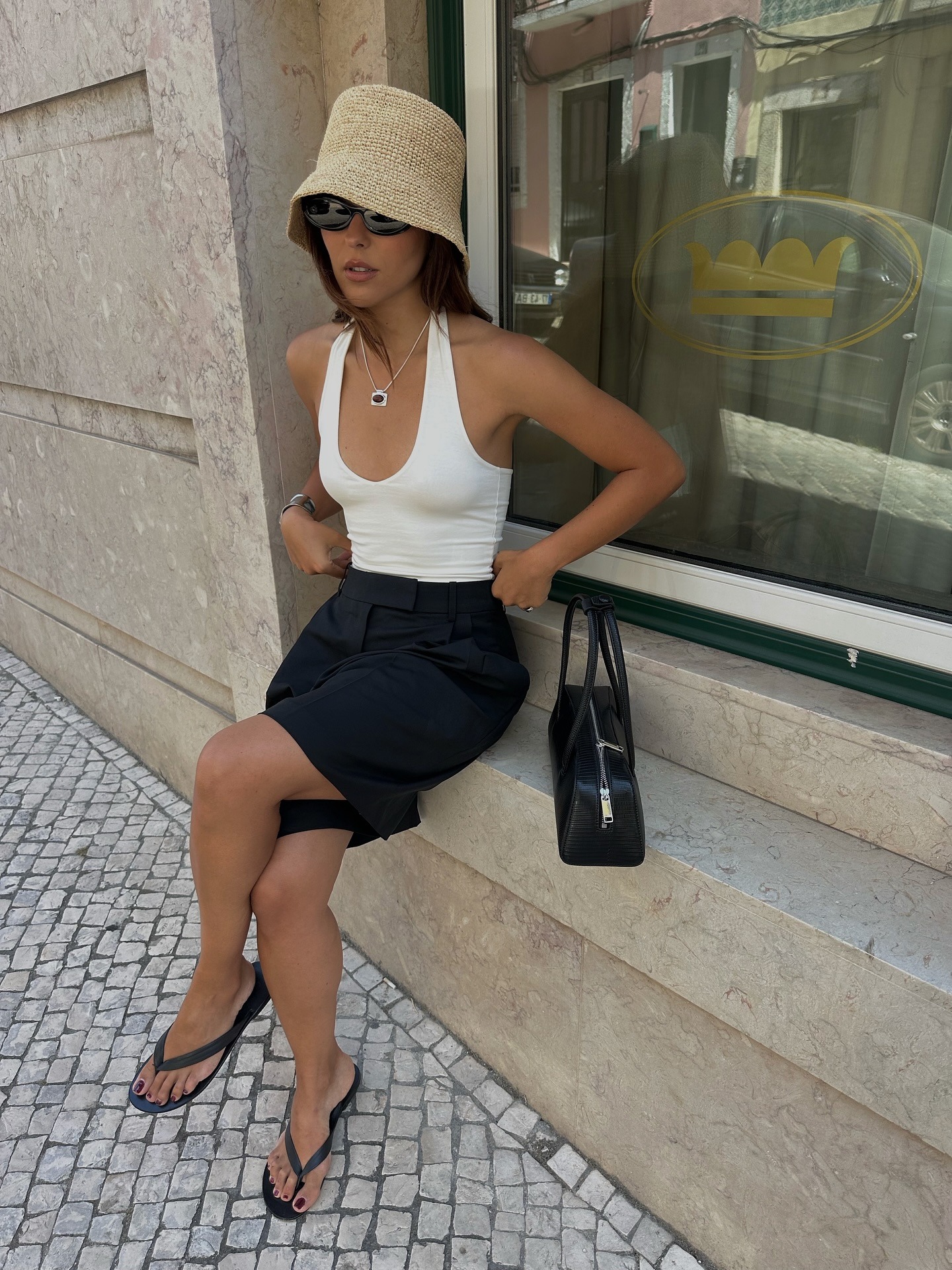 Woman in white halter top and black Bermuda shorts.