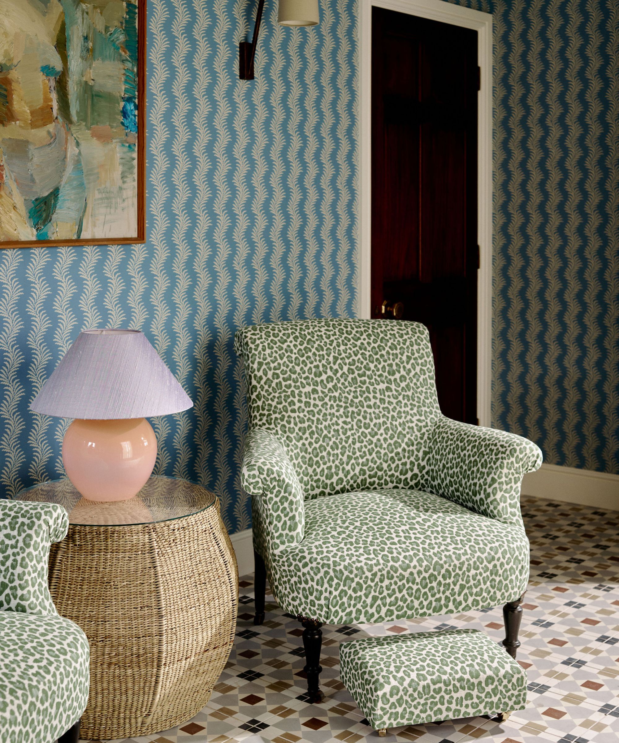 a hallway with two animal print chairs for reading, a rattan side table with a pink and lilac lap, blue botanical stripe wallpaper and a checkerboard tile floor