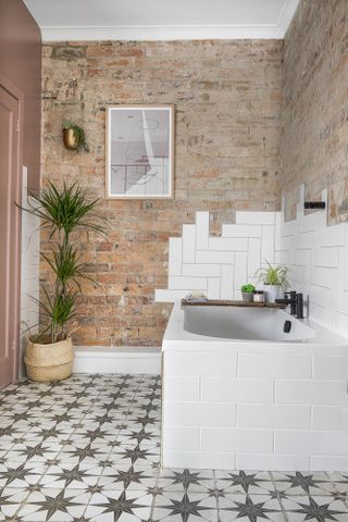 Bathroom with brick wall, white metro tiles, white bath and patterned tile flooring