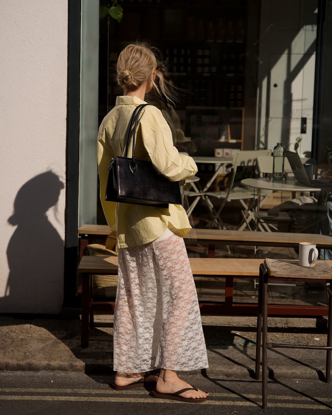 @chloekathbutler wears a white lace maxi skirt, yellow button-up shirt, black leather flip-flops and black shoulder bag