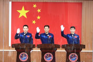 The crew of China's Shenzhou-12 astronaut flight to the country's new space station waves to reporters in a press conference at the Jiuquan Satellite Launch Center on June 16, 2021. They are (from left): Tang Hongbo, Nie Haisheng and Liu Boming.