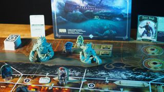 Unfathomable tokens, cards, board, and box on a wooden table, against a black background