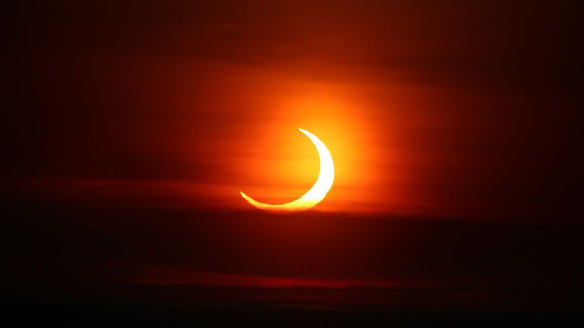 the sun looks like a crescent as the moon partially obscured a majority of the solar disk at sunrise.