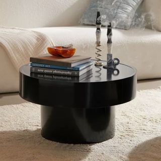 A black Urban Outfitters Eclipse Coffee Table, set with coffee table books and candles