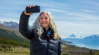 Woman photographing remote landscape with phone