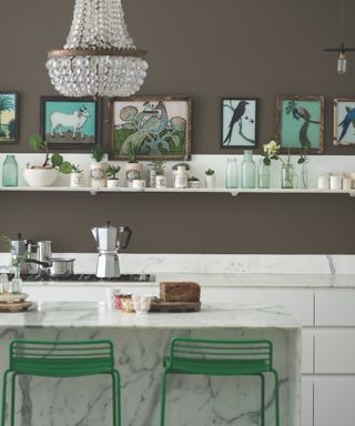 Kitchen with gray walls, white cabinets, chandelier, pops of green, bar stools, accessories, vases and artwork