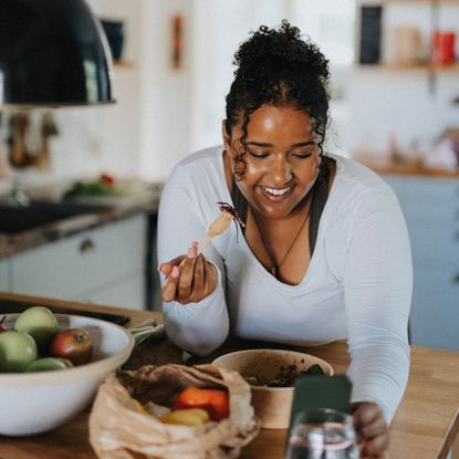 30-30-30 eating method: A woman following a healthy recipe on her phone in the kitchen