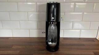 The Sodastream Spirit One Touch in the middle of carbonating water on a kitchen countertop