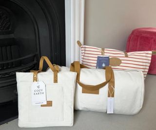 Cozy Earth bedding in branded bags against a fireplace and a gray wall.