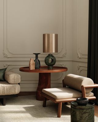 A living area with a small round wooden table, a chaise longue, and a lamp with a circular base and a brass shade