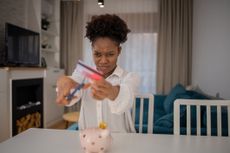 A young woman cuts up one of the worst credit cards with a scowl on her face.