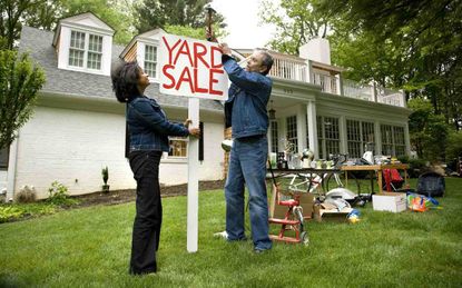 Mature couple putting up sign for Yard Sale