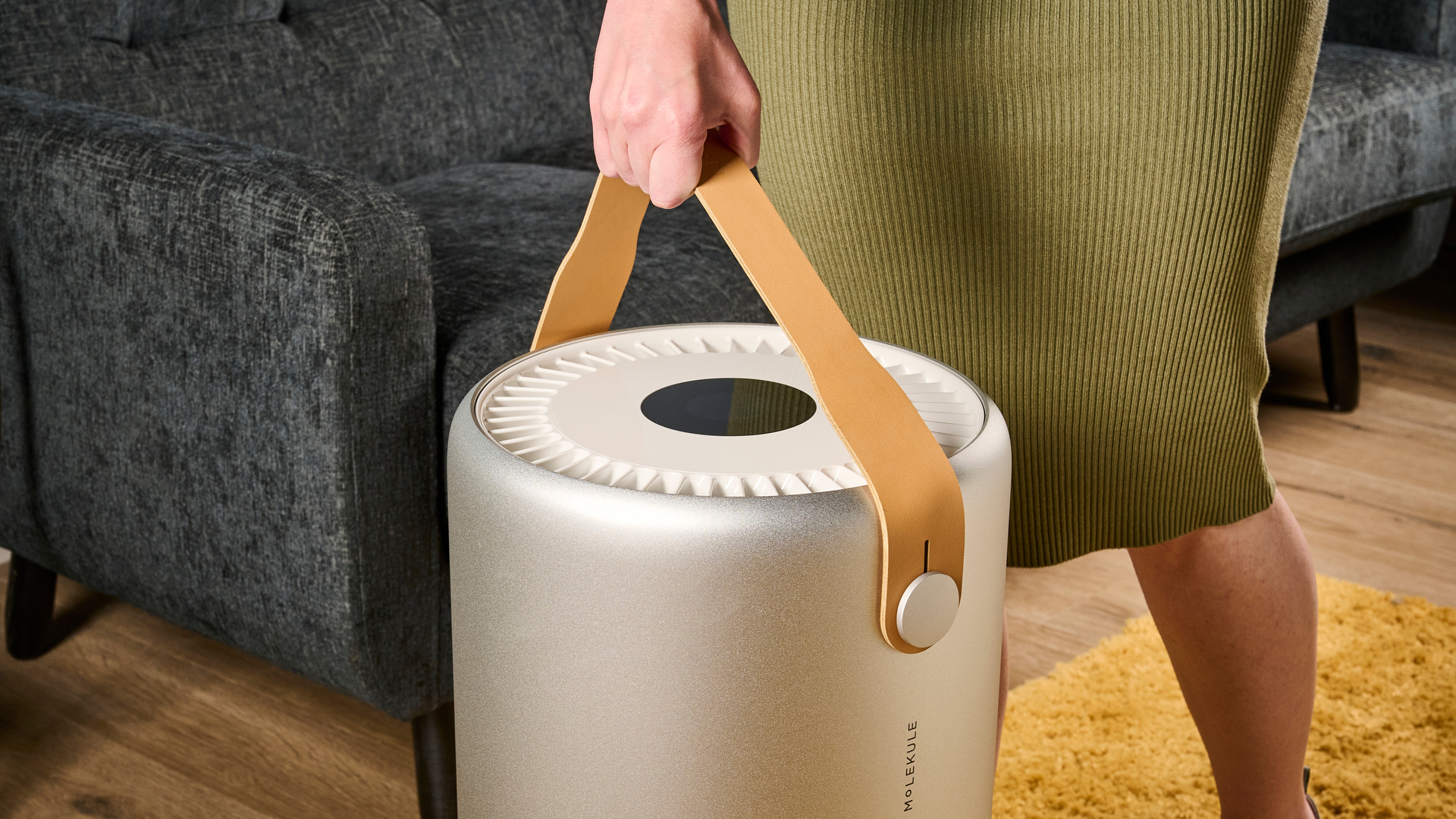 Image shows the Molekule Air Pro air purifier being lifted by its faux leather strap.