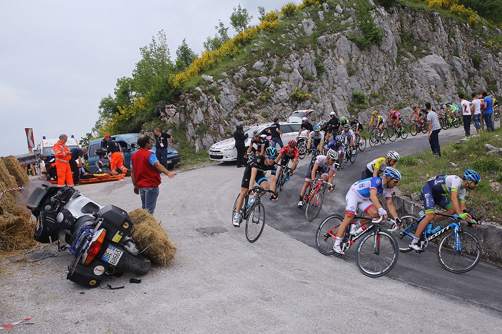 The peloton rides past the motorbike accident
